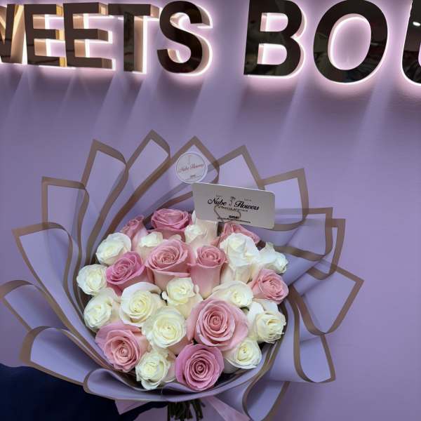 Bouquet of pink and white roses wrapped in lilac paper