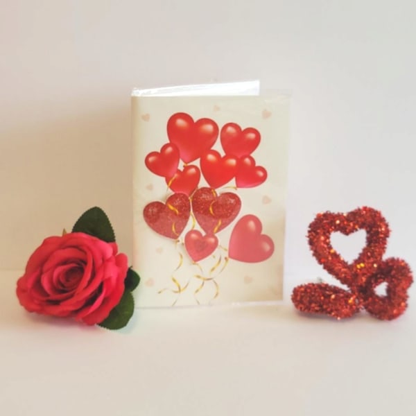 Red rose with a heart-themed greeting card and glitter heart decoration