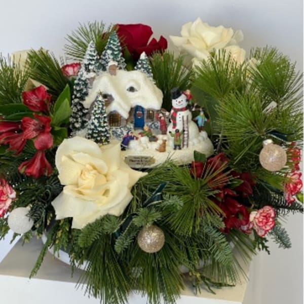 Christmas floral arrangement with white and red roses and a snowy village ornament