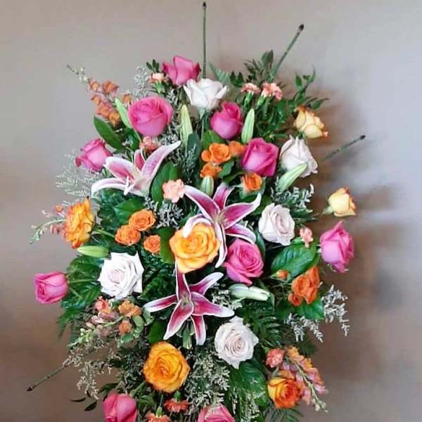 Standing floral spray with pink, white, and orange roses and lilies