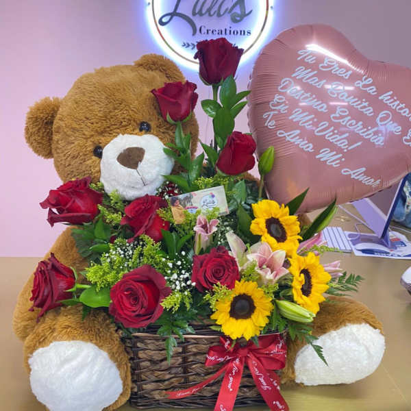 Teddy bear with roses and sunflowers in a basket beside a heart balloon