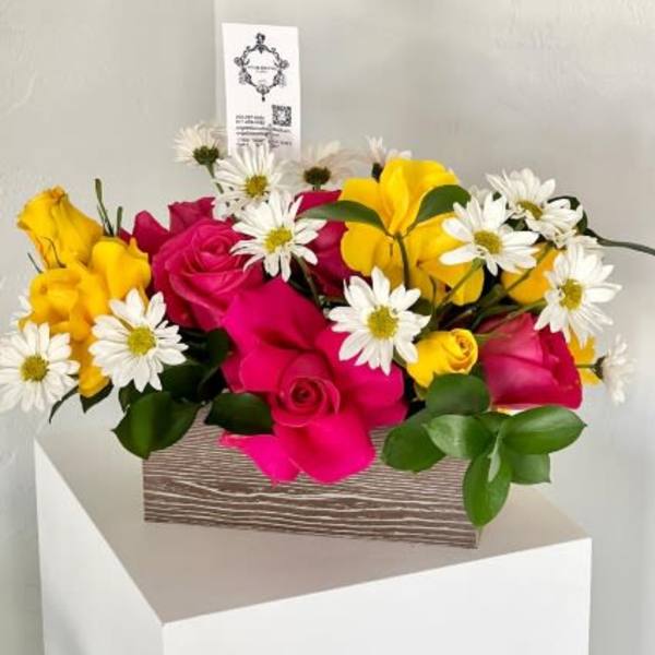 Pink and yellow roses with white daisies in a wooden box