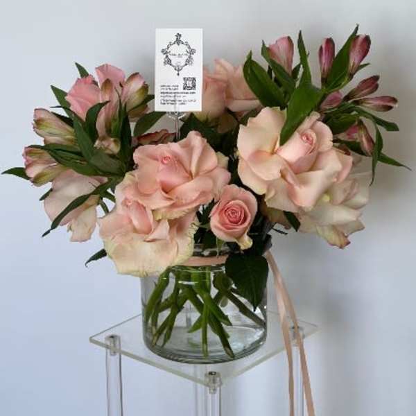 Pink roses and alstroemeria in a glass vase with a ribbon