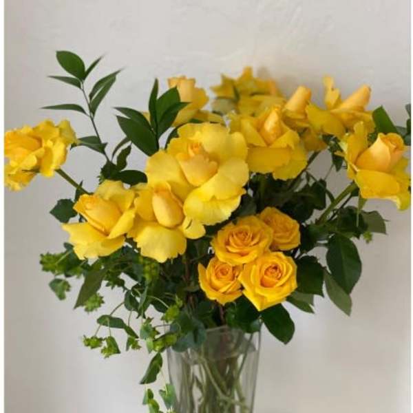 Yellow roses and yellow blooms in a clear glass vase