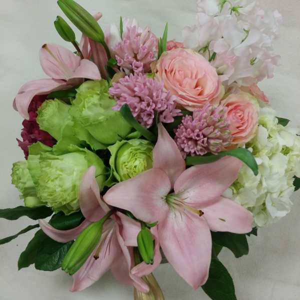 Pink lilies and roses with green blooms in a hand-tied bouquet