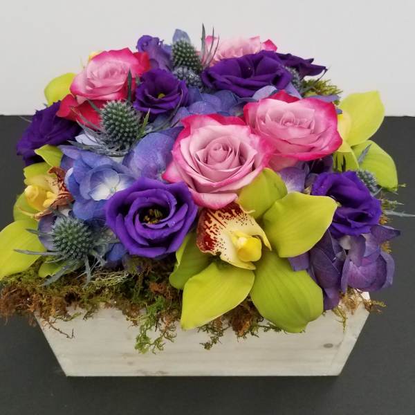 Purple and pink rose arrangement with orchids in a white box