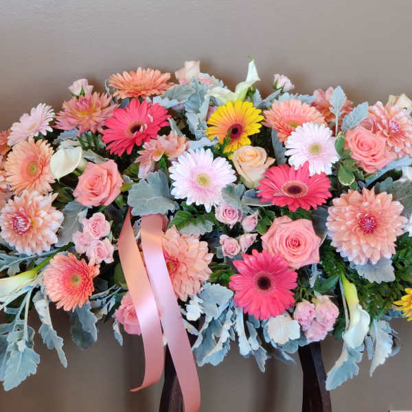 Large pastel floral arrangement with pink and white blooms and ribbon