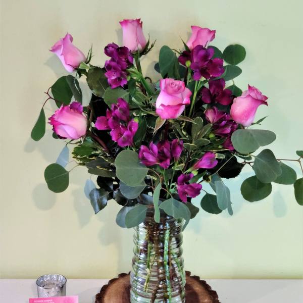 Pink roses and purple flowers arranged in a glass vase
