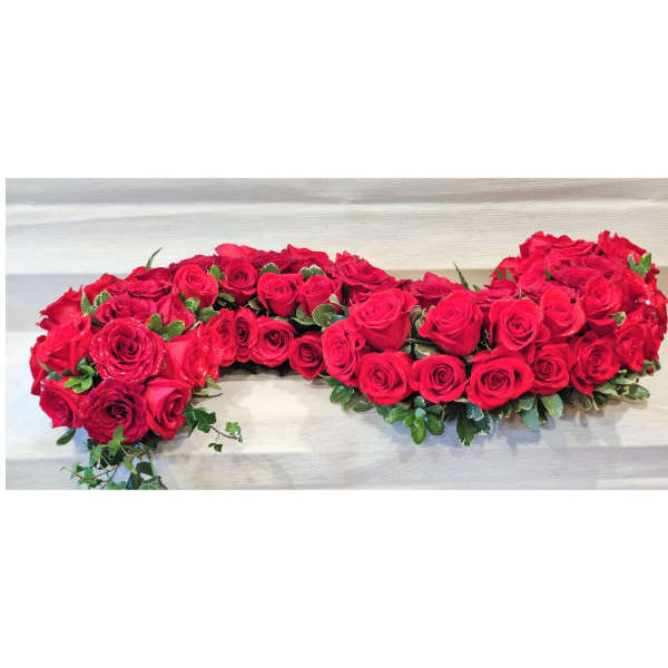 Heart-shaped arrangement of red roses with greenery