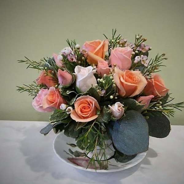 Pink and peach roses arranged in a low white bowl