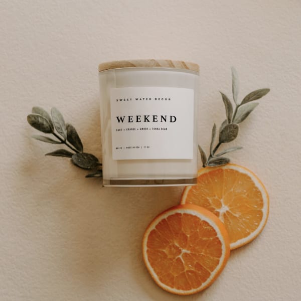 Scented candle in a glass jar with orange slices and faux greenery