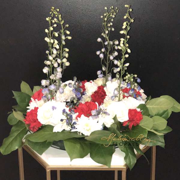 Red and white floral arrangement with tall lavender stems in a gold stand