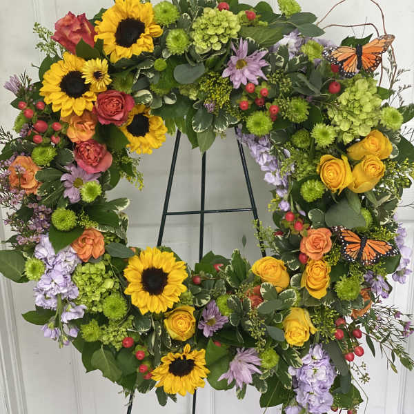 Heart-shaped floral wreath with sunflowers, roses, and butterflies