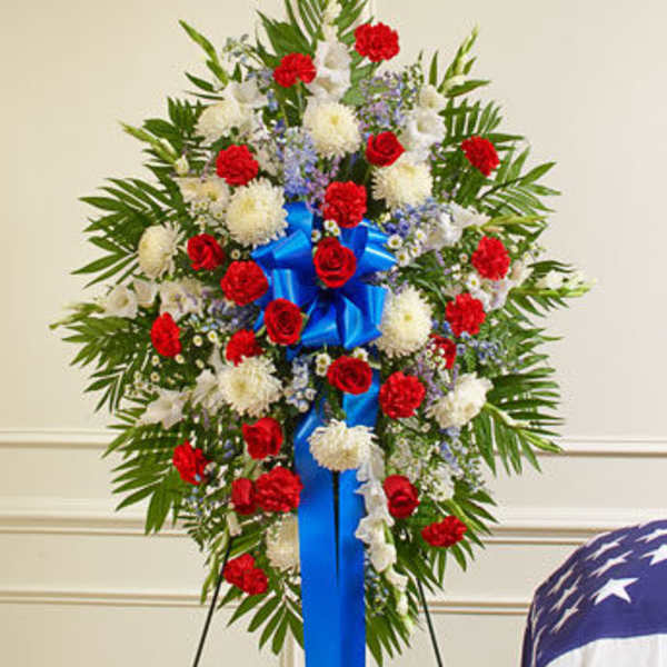 Standing floral spray with red and white flowers and a blue ribbon