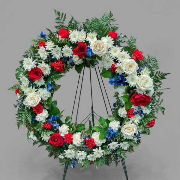 Circular floral wreath on a stand with red, white, and blue flowers