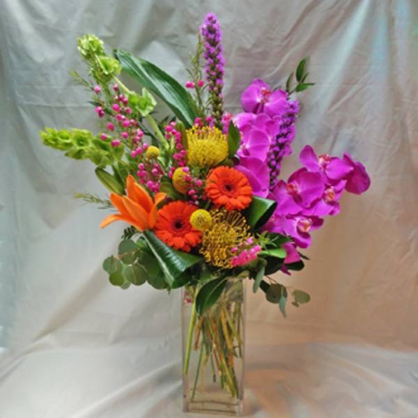 Bright mixed bouquet in a clear glass vase with orange, pink, and yellow blooms