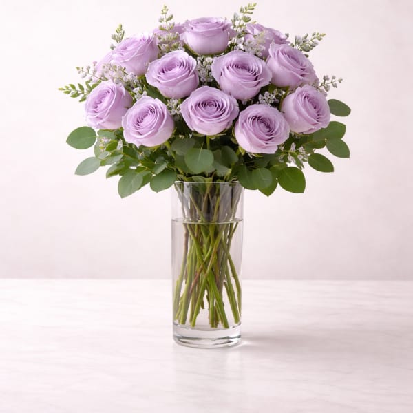 Tall glass vase with a dozen light lavender roses arranged in a rounded bouquet