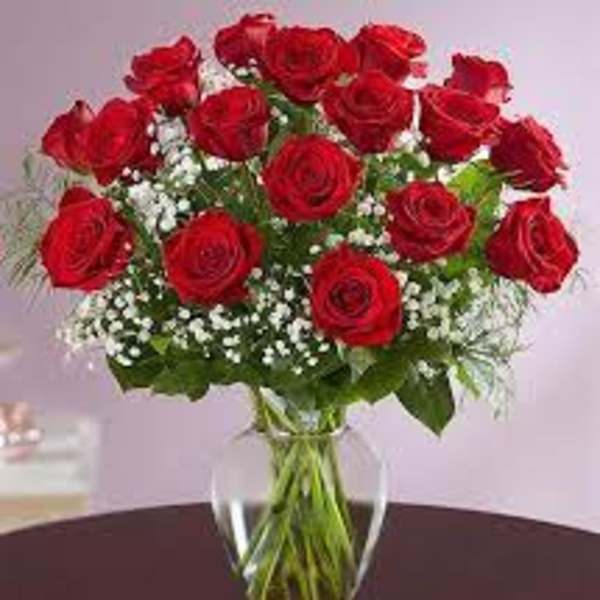 Arrangement of red roses with white filler flowers in a clear glass vase on a table