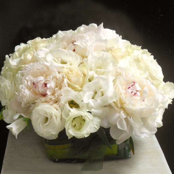 White bouquet of peonies and roses in a low container