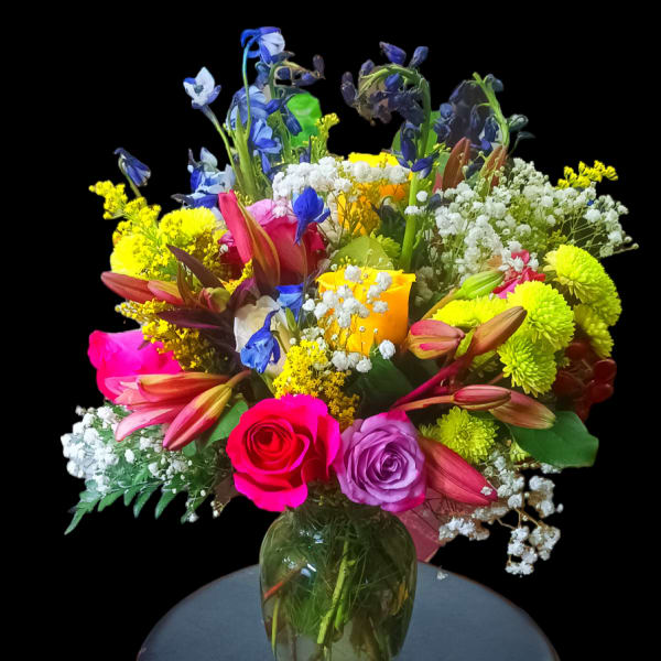 Colorful mixed bouquet in a glass vase on a stool