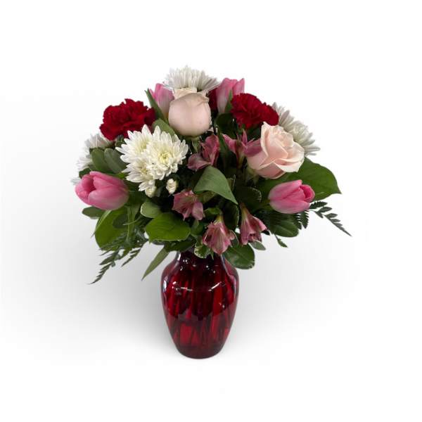 Mixed bouquet in a red glass vase with pink, white, and red blooms