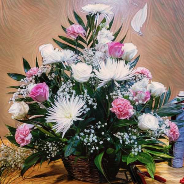 Pink and white floral arrangement in a wicker basket