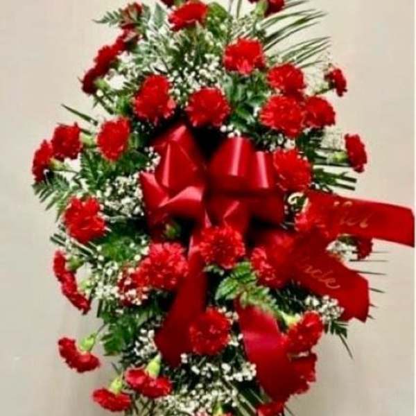 Tall standing spray of red carnations with a large red bow on an easel