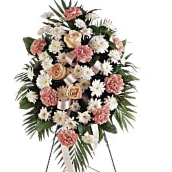 Standing spray of peach roses, pink carnations, and white daisies on a metal easel.