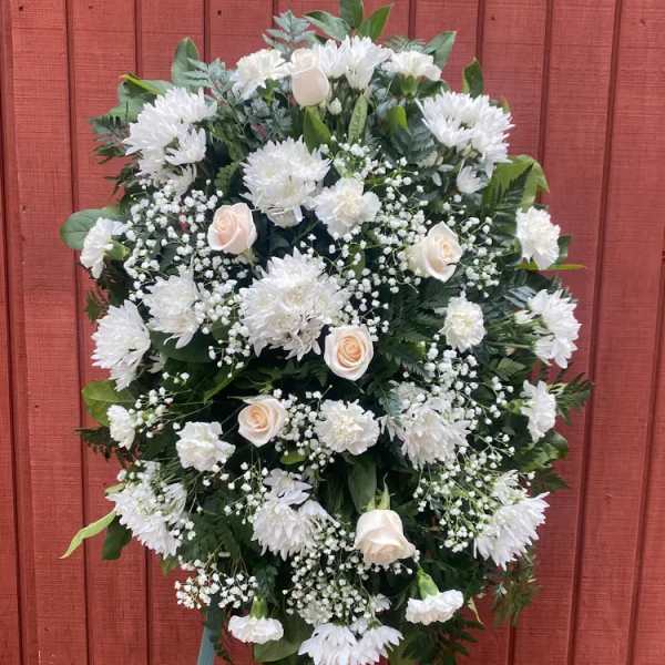 Oval standing spray of white flowers and ivory roses on an easel.