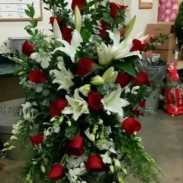 Tall arrangement of red roses and white lilies in a cascading standing spray