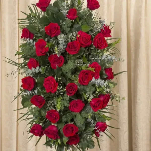 Standing spray of red roses arranged in an oval shape on an easel