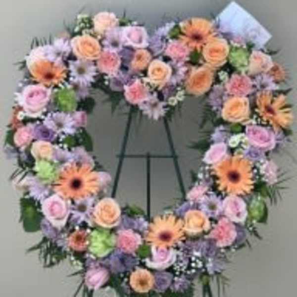 Heart-shaped floral wreath on a standing easel with pastel blooms