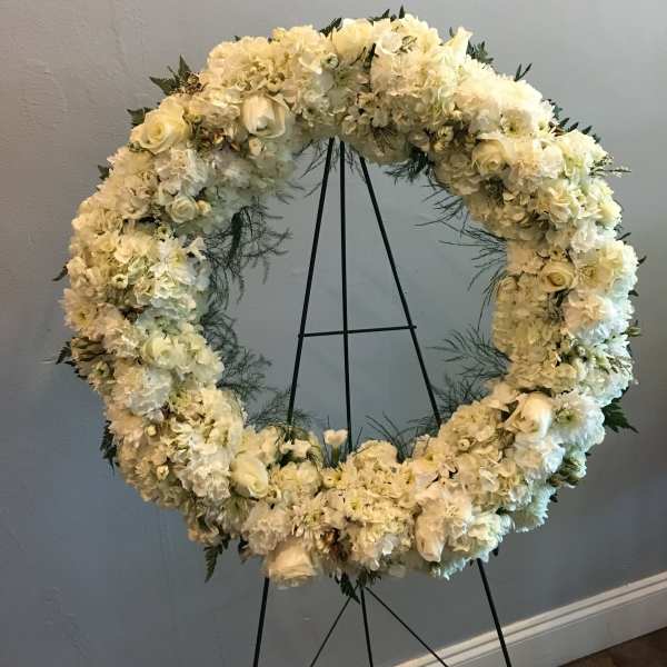White floral wreath on a black stand