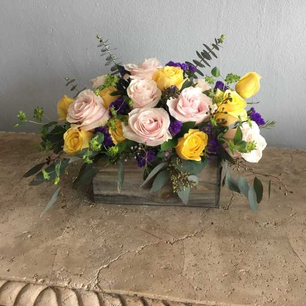 Arrangement of pink and yellow roses in a wooden box