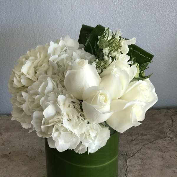 White roses and hydrangeas arranged in a green vase