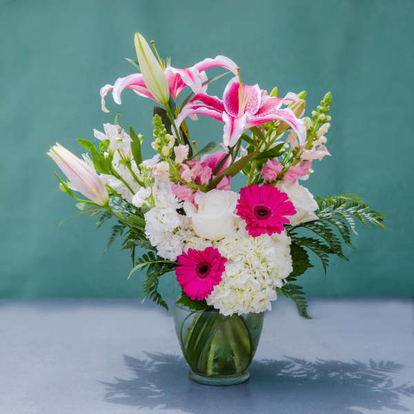 Pink lilies, white roses, and gerbera daisies in a glass vase