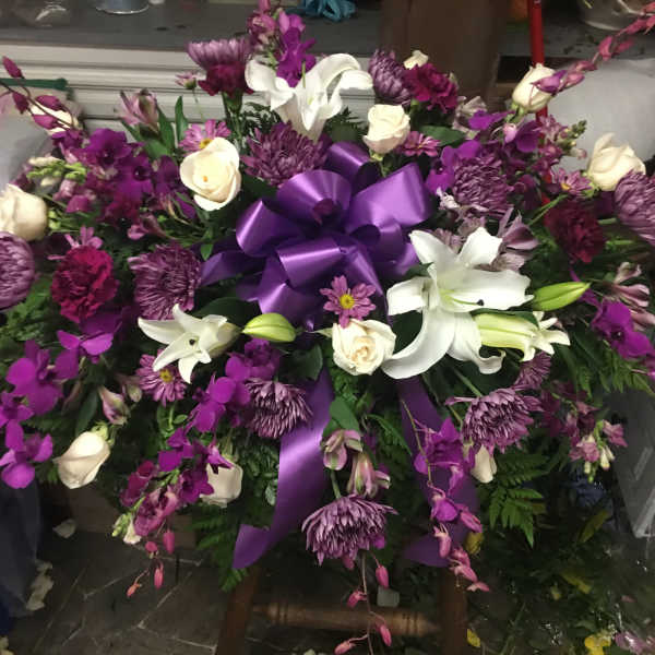 Large purple and white floral spray with a satin ribbon bow