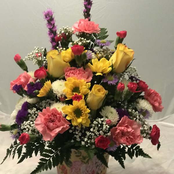 Colorful mixed flower arrangement in a floral tin container