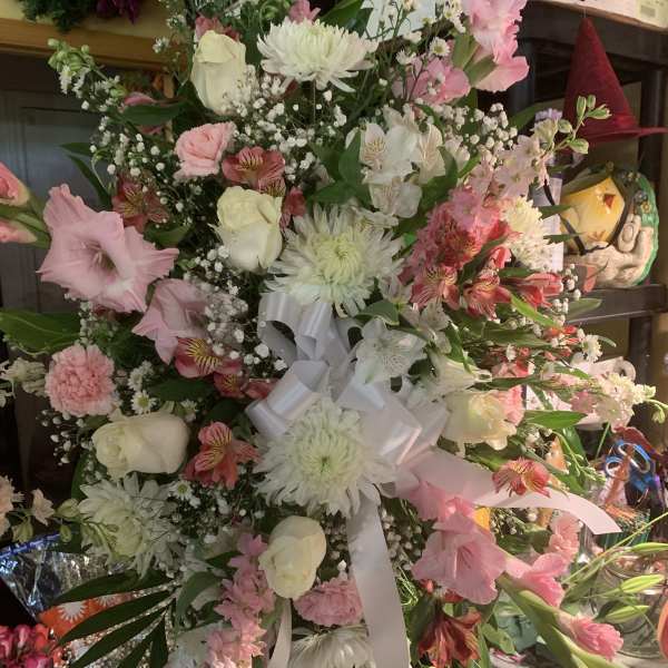 Large pink and white floral spray with a white ribbon bow