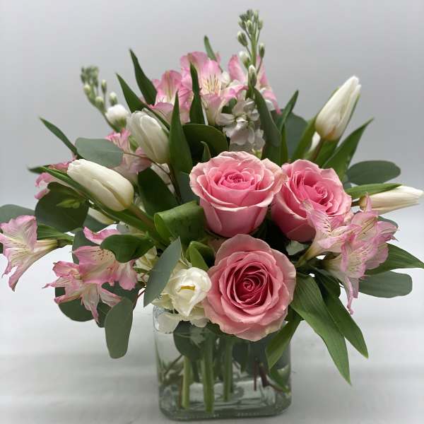 Pink roses and white tulips in a clear glass vase