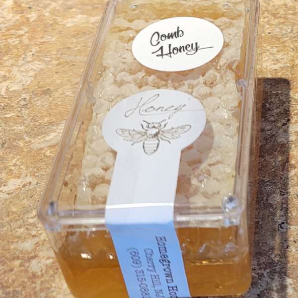 Plastic container of comb honey with labels on a countertop
