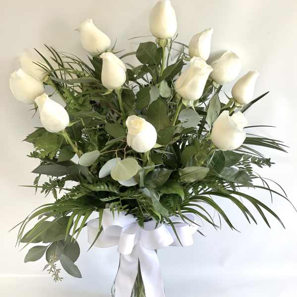 White roses in a glass vase with a white ribbon