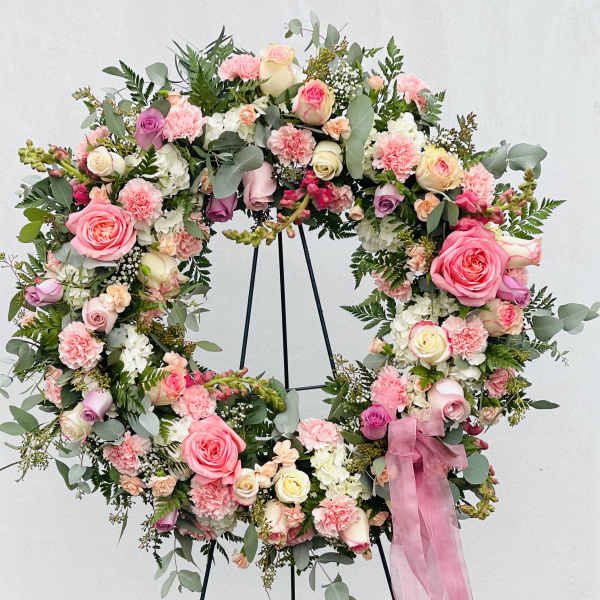 Heart-shaped floral wreath with pink and cream roses on a stand