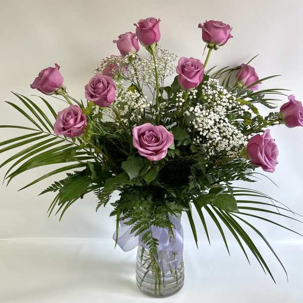 Pink roses arranged in a clear glass vase with baby's breath
