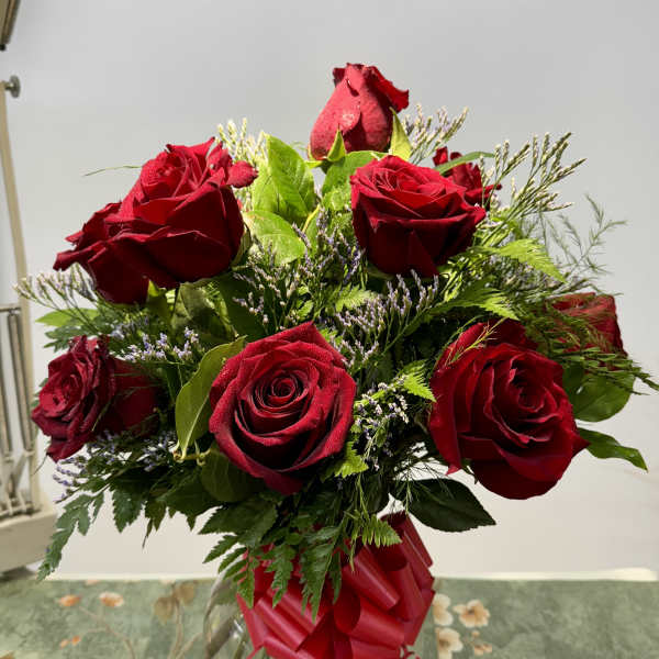 Red roses arranged in a clear glass vase with a red ribbon
