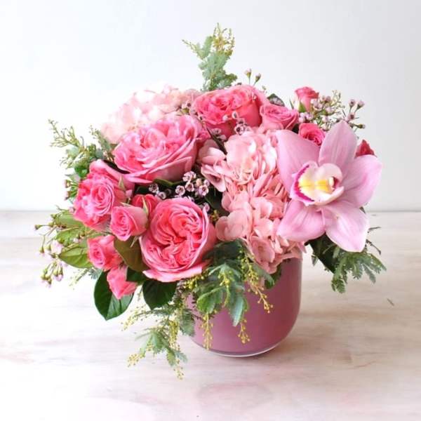 Pink rose and orchid arrangement in a pink vase