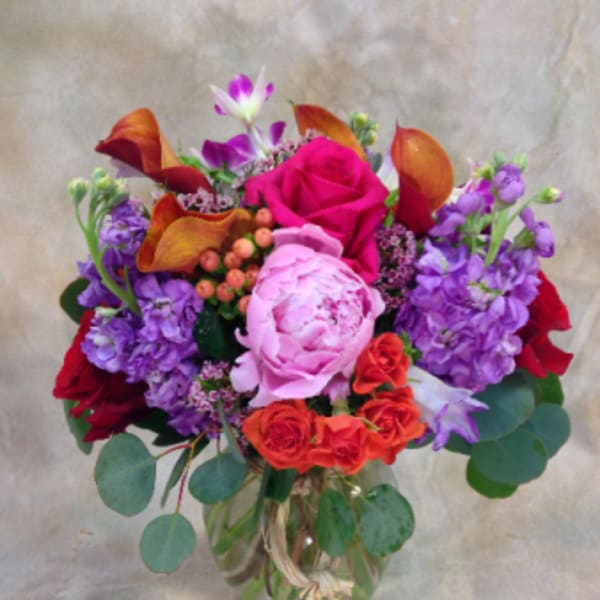 Mixed bouquet of pink, purple, orange, and red flowers in a glass vase