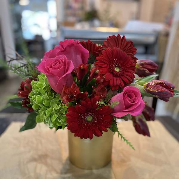 Pink roses and red gerbera daisies in a gold vase