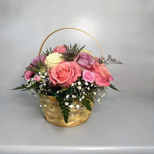 Basket of pink, cream, and lavender roses with baby's breath