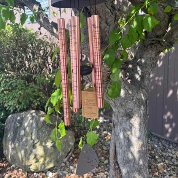 Copper wind chime hanging from a tree branch